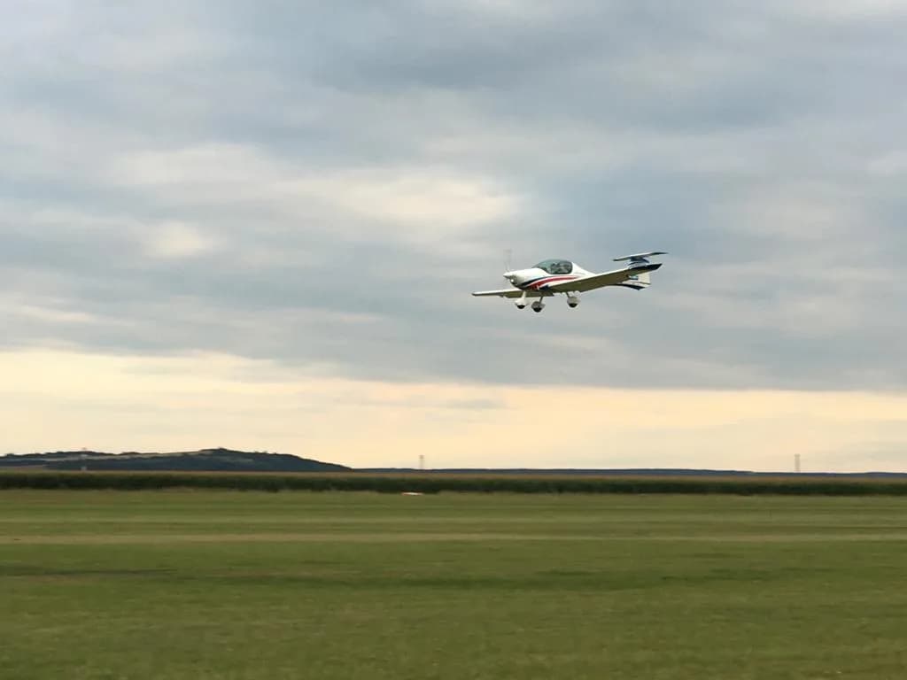 Letoun Atec 321 Faeta v nízkém letu nad travnatou plochou