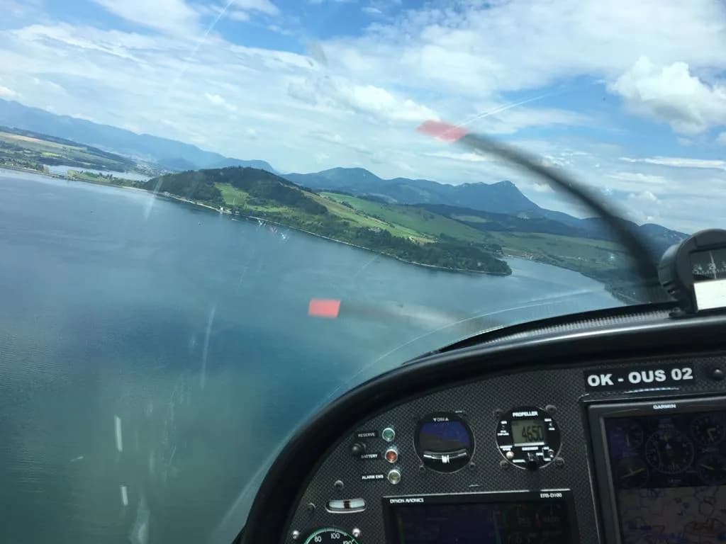 Horské jezero před letadlem z pohledu přes přístrojovou desku