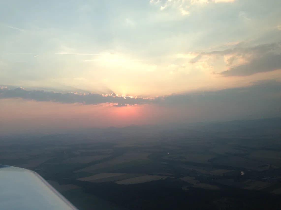 Zapadající slunce nad krajinou z pohledu z letadla